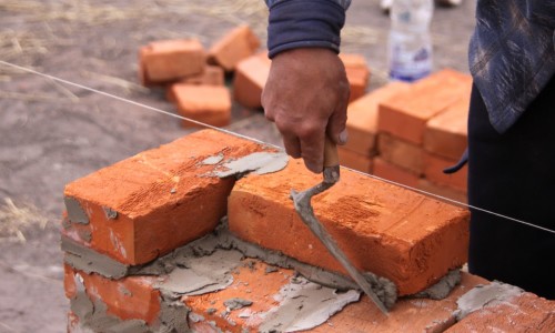 Muratore in a elmetto protettivo costruzione mattone